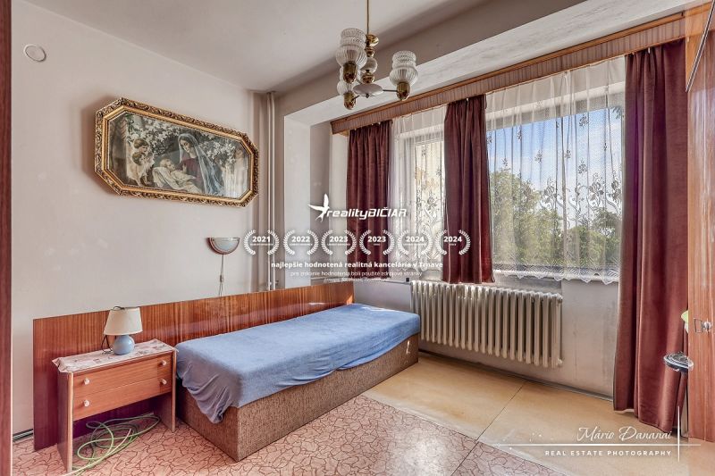 6-izbový rodinný dom v obci Biely Kostol - Izba s posteľou, obrazom a závesmi v rodinnom dome.