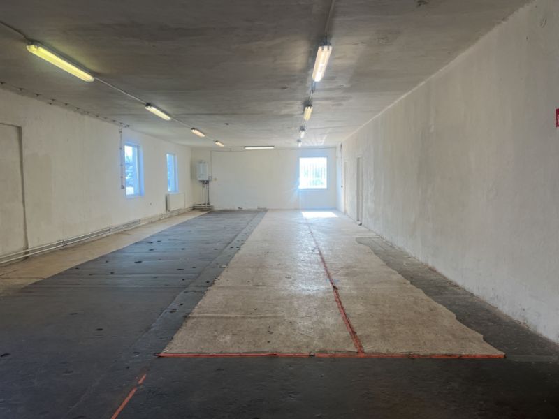 Skladové a výrobné priestori s kanceláriami 130 m² /180 m² /198 m² BB - Prázdna interiérová miestnosť v Sklady a haly s betónovou podlahou a osvetlením.