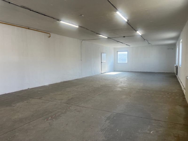 Skladové a výrobné priestori s kanceláriami 130 m² /180 m² /198 m² BB - Priestranný prázdny interiér s betónovou podlahou a bielymi stenami v skladoch a halách.
