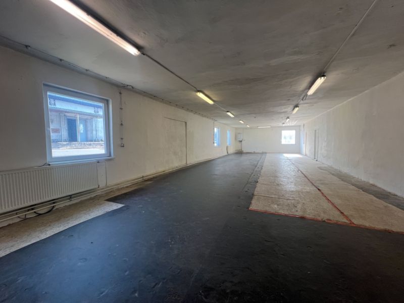 Skladové a výrobné priestori s kanceláriami 130 m² /180 m² /198 m² BB - Interiérová fotografia znázorňuje prázdny priestor s čiernou podlahou a oknami, Sklady a haly.