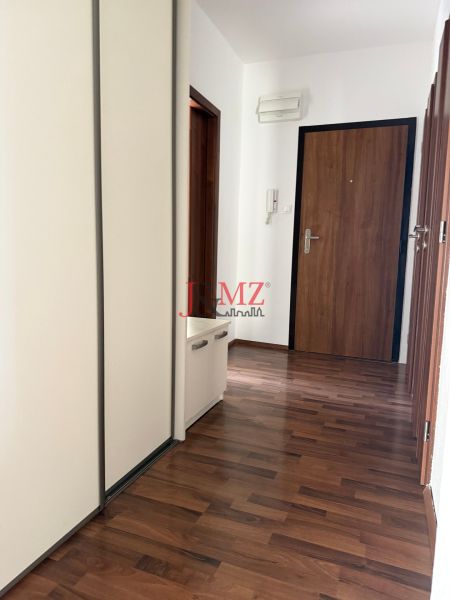 Prenájom 3-izb. byt Ku Bratke - zariadený - Vstupná chodba v 3-izbovom byte s podlahou s dreveným dekorom a bielymi skriňami.