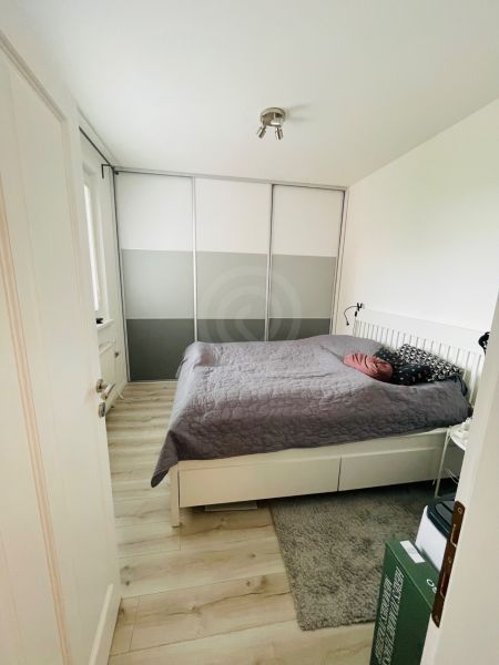 Na predaj 3.izb.byt v Petržalke pri novej elek.trati.65m2 - Spálňa v 3-izbovom byte s podlahou s dreveným dekorom a veľkou skriňou.