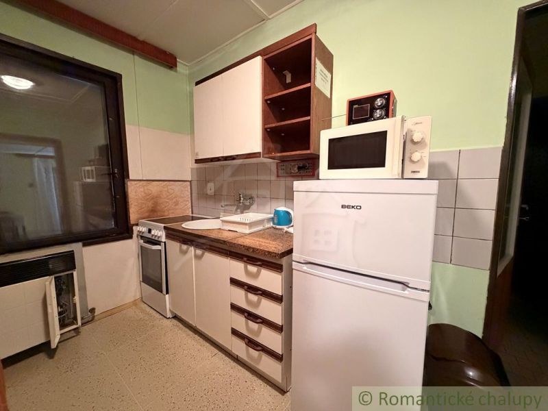 AREÁL 3 REKREAČNÝCH CHÁT PRI PODHÁJSKEJ – IDEÁLNE PRE DETSKÉ TÁBORY, R - Kuchynský kút so spotrebičmi v chate, podlaha s dreveným dekorom.