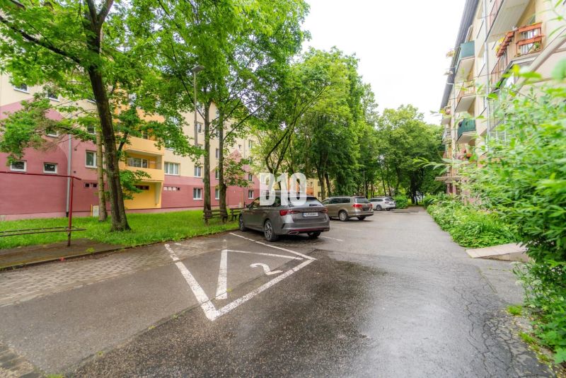 2 izbový kompletne zariadený byt Sever na prenájom - Parkovisko s autami a obytnými domami obklopené zeleňou v Martine.