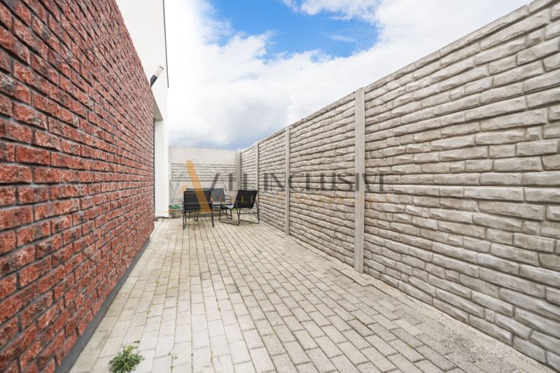 NA PREDAJ 4 IZBOVÝ RODINNÝ DOM - NOVOSTAVBA, ŠAMORÍN - Dlaždený dvor s tehlovým plotom a vonkajším sedením pri rodinnom dome, pod modrou oblohou.
