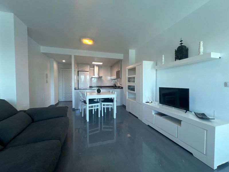 Na predaj apartmán - Mar Menor, Španielsko A500ZL - Rekreačný apartmán s pohovkou, jedálenským stolom a TV, podlaha s dreveným dekorom.