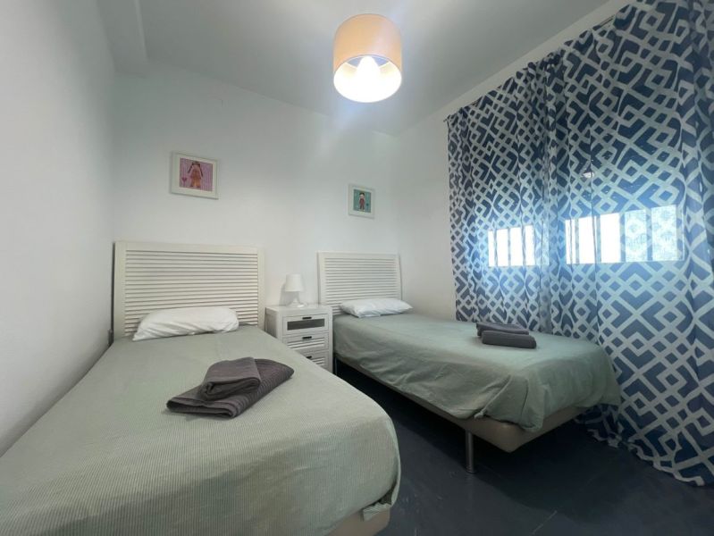 Na predaj apartmán - Mar Menor, Španielsko A500ZL - Rekreačný apartmán s dvomi jednolôžkovými posteľami, vzorovanými závesmi a stolíkom s lampou.