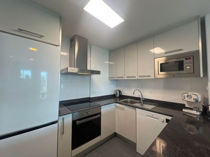 Na predaj apartmán - Mar Menor, Španielsko A500ZL - Kuchyňa v rekreačnom apartmáne s bielymi skrinkami, spotrebičmi a čiernou pracovnou doskou.