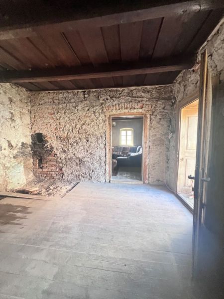Na predaj vidiecky rodinný dom - Žarnovica/Brehy D045ZL - Kamenné steny a dvere do miestnosti v rodinnom dome so starým nábytkom.