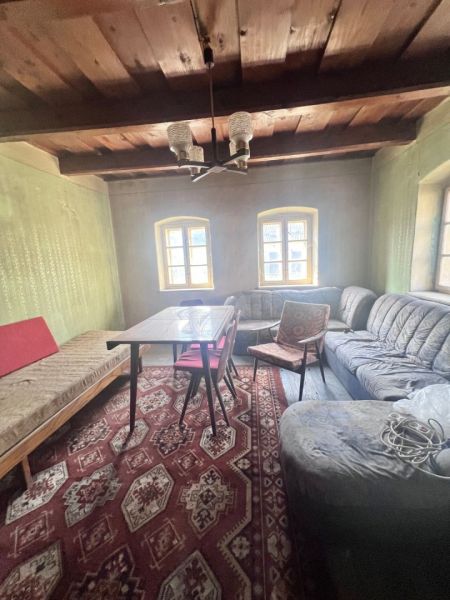 Na predaj vidiecky rodinný dom - Žarnovica/Brehy D045ZL - Obývacia izba v rodinnom dome s dreveným stropom, sedačkou a vzorovaným kobercom.