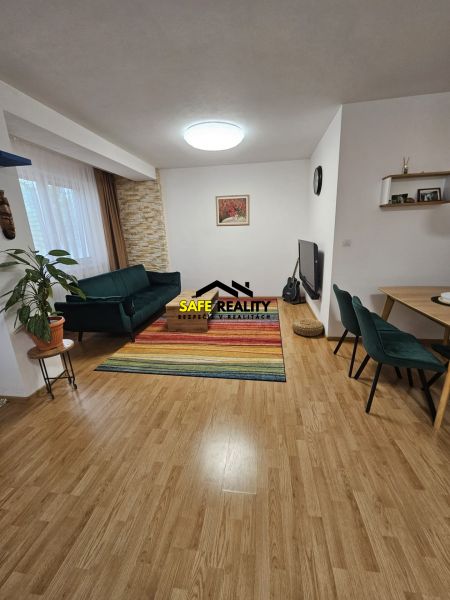 3 - izbový byt Žilina - Závodie, Exkluzívne - Obývačka 3-izbového bytu s pestrým kobercom a podlahou s dreveným dekorom.