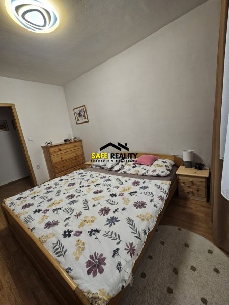 3 - izbový byt Žilina - Závodie, Exkluzívne - Spálňa v 3-izbovom byte s posteľou, komodou a podlahou s dreveným dekorom.