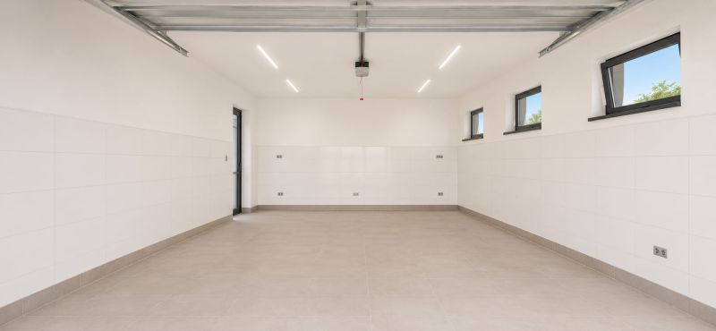 NOVOSTAVBA V NADŠTANDARDE | MODERNÝ 4-IZBOVÝ DOM S GARÁŽOU, REKUPERÁCI - Priestranná garáž s bielymi stenami a oknami, Rodinný dom.