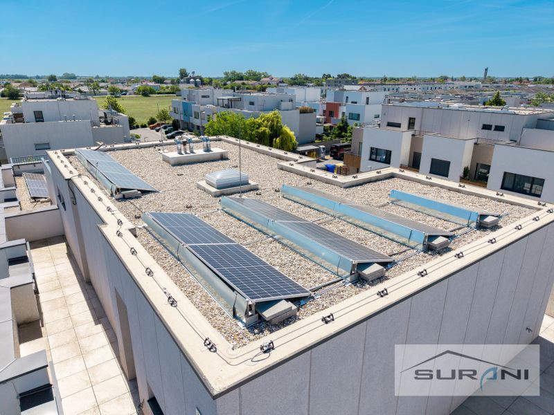 Nový 3-izbový byt 82 m² | Terasa 97 m² | Mesačná ulica | Hviezdoslavov - Budova so solárnymi panelmi na Mesačnej ulici v Hviezdoslavove obklopená zástavbou.