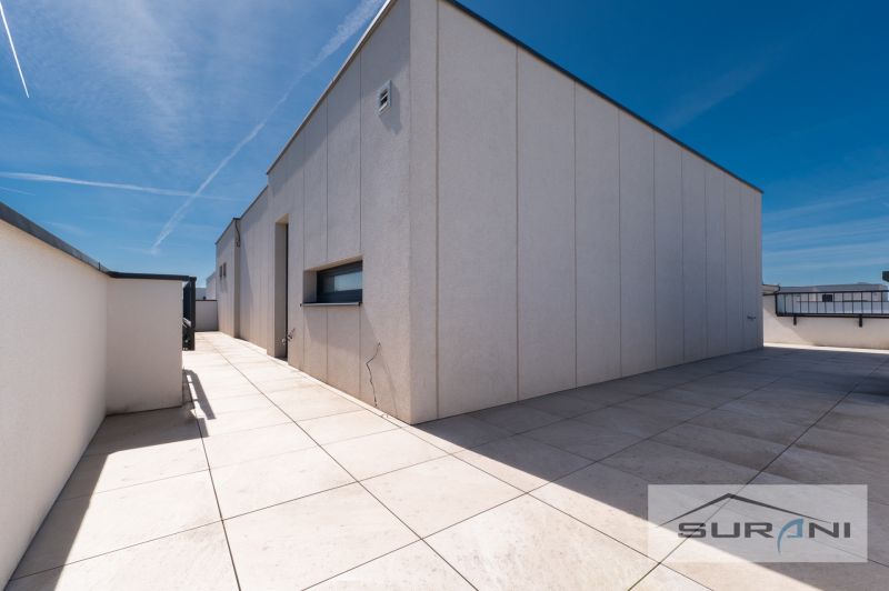 Nový 3-izbový byt 82 m² | Terasa 97 m² | Mesačná ulica | Hviezdoslavov - Terasa 3-izbového bytu na Mesačnej ulici v Hviezdoslavove, biele steny, modrá obloha.