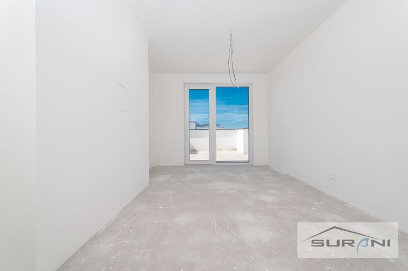 Nový 3-izbový byt 82 m² | Terasa 97 m² | Mesačná ulica | Hviezdoslavov - Prázdna miestnosť s betónovou podlahou a balkónovými dverami v 3-izbovom byte.