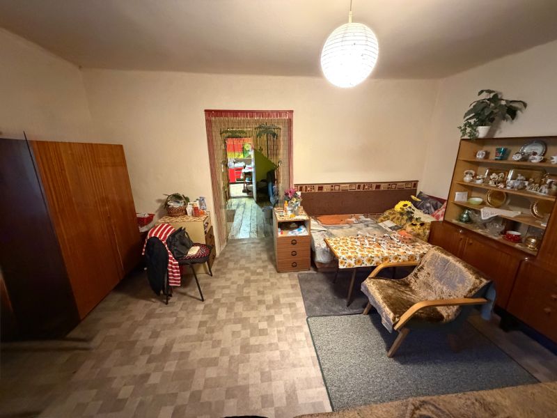 Rodinný dom s veľkým pozemkom v meste Nesvady  - Obývacia izba v rodinnom dome so starožitným nábytkom a kreslami, podlaha s dreveným dekorom.