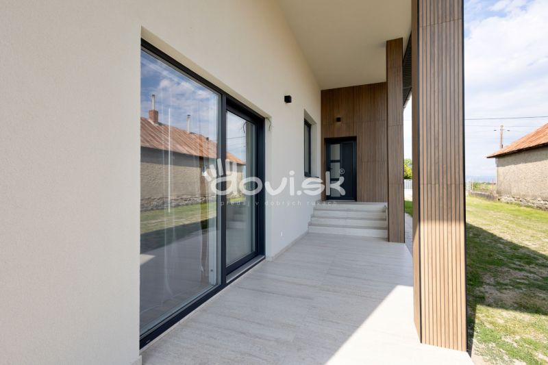 MODERNÝ 4-IZBOVÝ BUNGALOV | ZEMPLÍNSKA ŠIROKÁ - Rodinný dom v Zemplínskej Širokej s terasou, drevenými detailmi a trávnikom.