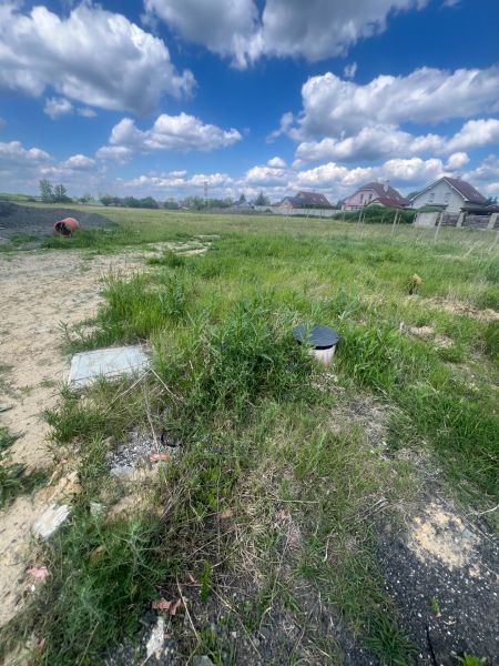 Pozemok v obci Veľké Leváre  - Pozemky na bývanie vo Veľkých Levároch s trávnatou plochou a vidiekom v pozadí.