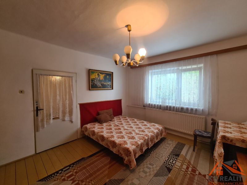 Na predaj rodinný dom Dulovce ! - Spálňa v rodinnom dome s ozdobným lustrom, závesmi a kobercom.
