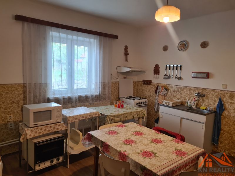 Na predaj rodinný dom Dulovce ! - Kuchyňa v rodinnom dome s mikrovlnkou, kachľami, stolom a drezom.