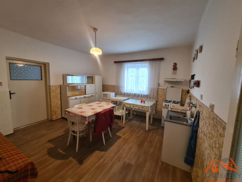 Na predaj rodinný dom Dulovce ! - Kuchyňa v rodinnom dome s podlahou s dreveným dekorom, jednoduchý nábytok a jedálenský stôl.