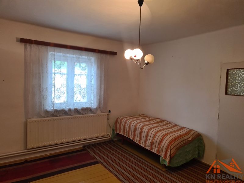 Na predaj rodinný dom Dulovce ! - Jednoduchá izba s posteľou a oknom, Rodinný dom, koberec a závesy.
