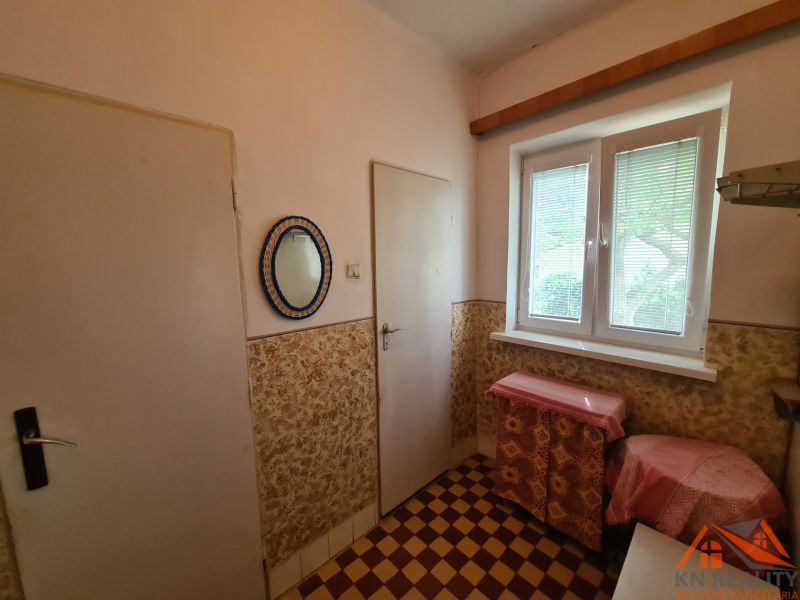Na predaj rodinný dom Dulovce ! - Interiér v rodinnom dome s kachličkovou podlahou a oknom so žalúziami.