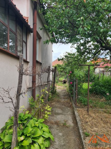 Na predaj rodinný dom Dulovce ! - Záhrada vedľa rodinného domu v Dulovciach s chodníkom a rastlinami.