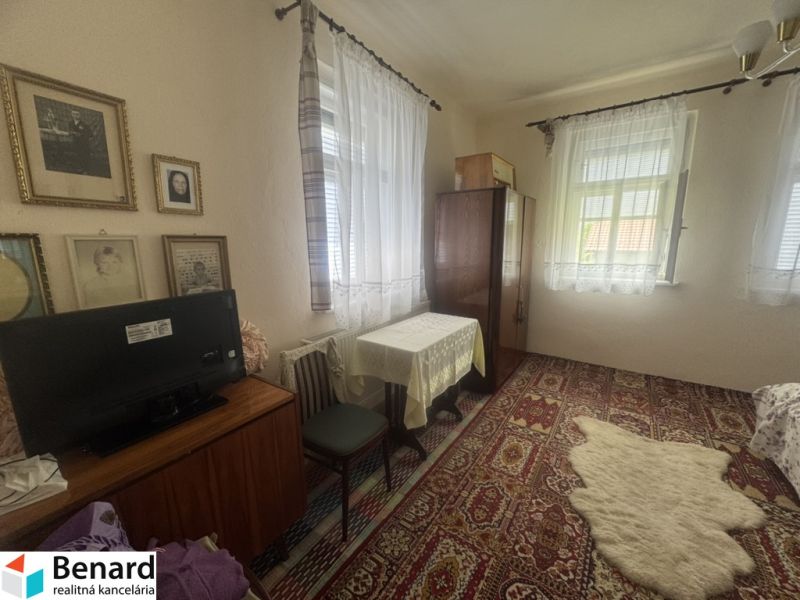 Rodinný dom Orlov - na predaj  - Izba s kobercom, stolom a TV v rodinnom dome. Vintage dekorácie na stenách.