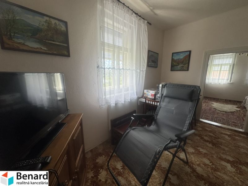 Rodinný dom Orlov - na predaj  - Obývacia miestnosť v rodinnom dome s TV, kreslom a dekoráciami na stenách.