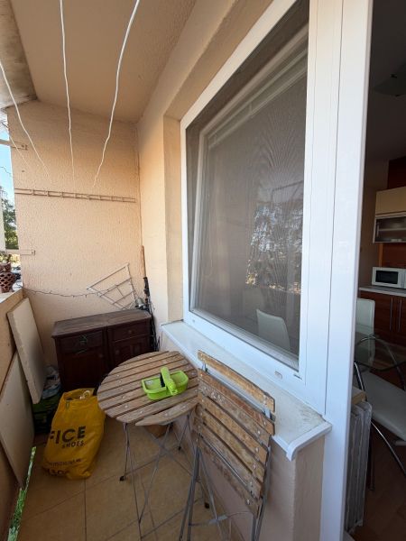 3 izbový byt s balkónom v meste Levice - Balkón 3-izbového bytu s dreveným stolom a stoličkami, vedľa kuchynského okna.