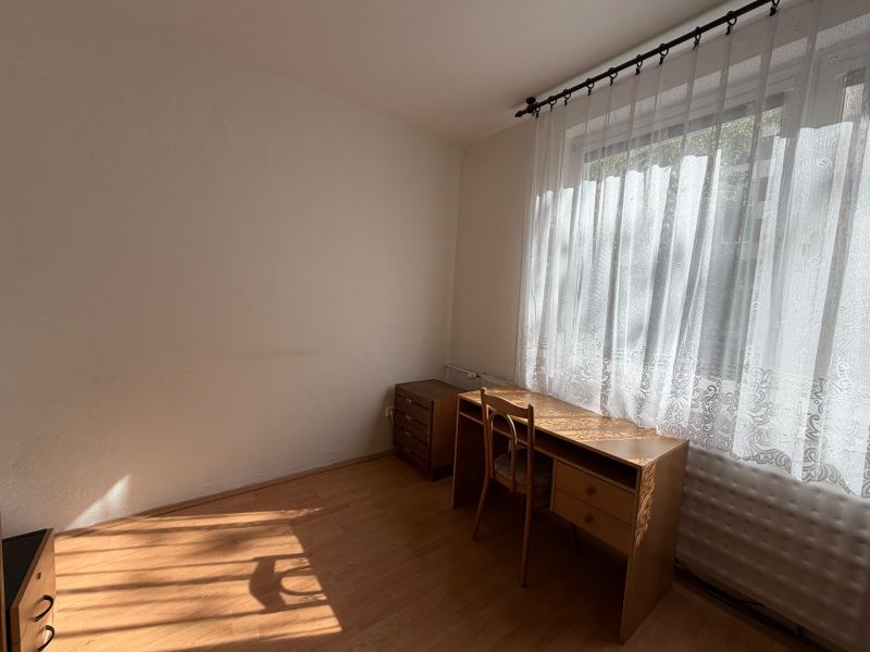 3 izbový byt s balkónom v meste Levice - Izba s pracovným stolom a stoličkou, podlaha s dreveným dekorom.