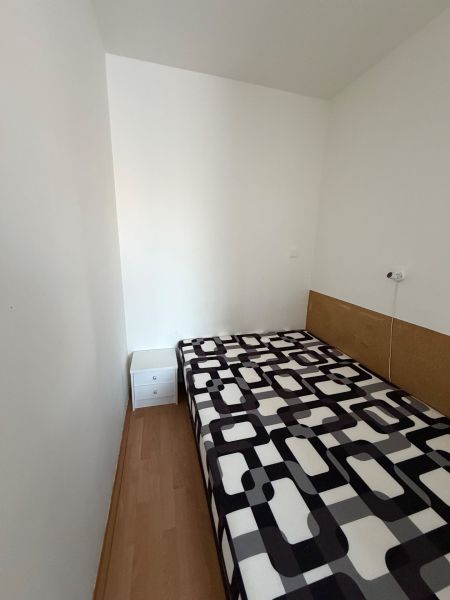 3 izbový byt s balkónom v meste Levice - Jednoduchá izba v 3-izbovom byte s posteľou a podlahou s dreveným dekorom.