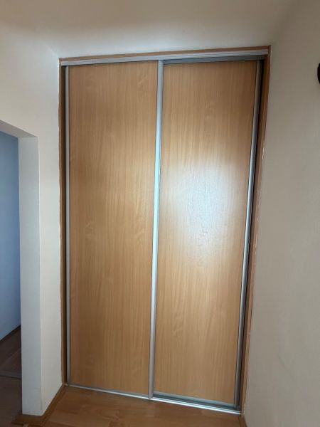 3 izbový byt s balkónom v meste Levice - Skriňa so zasúvacími dverami a podlahou s dreveným dekorom v 3-izbovom byte.