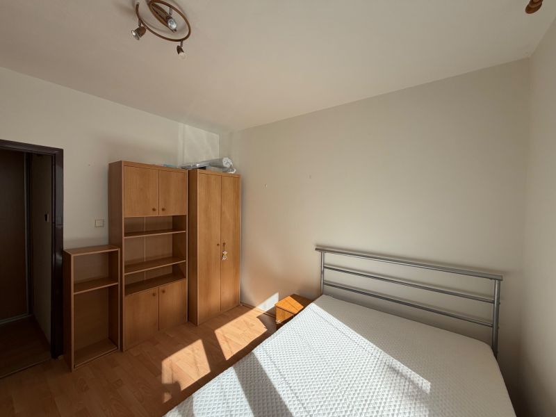 3 izbový byt s balkónom v meste Levice - Spálňa v 3-izbovom byte s bielymi stenami a podlahou s dreveným dekorom.