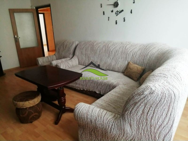 3 izbový byt na sidlisku Stráňany - Obývacia izba v 3-izbovom byte s rohovou sedačkou a podlahou s dreveným dekorom.