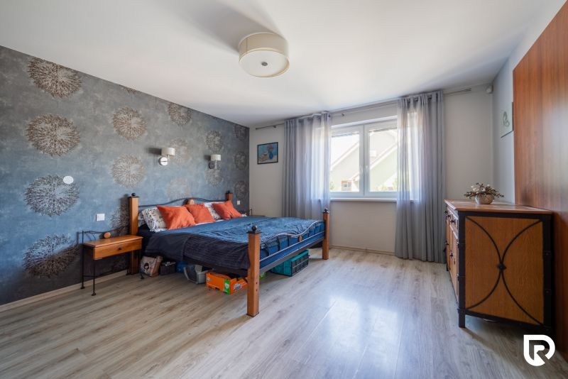 Predaj RD s pozemkom 1008 m2, Trenčín - Istebník - Spálňa v rodinnom dome s podlahou s dreveným dekorom, tapetou a masívnym nábytkom.
