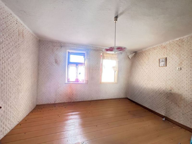 Na predaj 2 domy, ovocný raj a pokojné bývanie - Žirany D339ZL - Prázdna izba v rodinnom dome s podlahou s dreveným dekorom a kvetinovým lustrom.