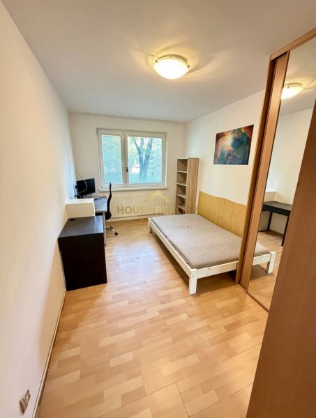 Prenájom pekný 4 izbový byt, Wolkrova ulica, Bratislava V. Petržalka - Izba v 4-izbovom byte s posteľou, pracovným stolom a podlahou s dreveným dekorom.