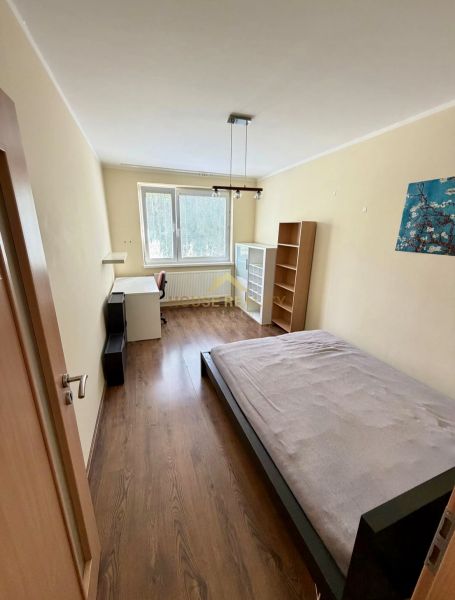 Prenájom pekný 4 izbový byt, Wolkrova ulica, Bratislava V. Petržalka - Spálňa v 4-izbovom byte s posteľou, stolom a podlahou s dreveným dekorom.