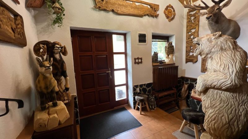 Na predaj penzion  – Štôla, Vysoké Tatry O560ZL - Interiér vily s drevenými sochami zvierat a vyrezávanými dekoráciami na stenách.
