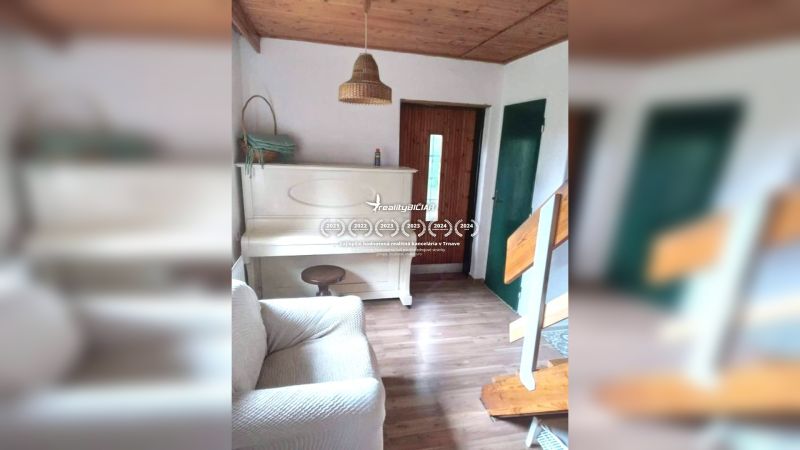 Exkluzívne na predaj, čarovný rodinný dom / chalupa v lone prírody - Interiér rodinného domu s bielym klavírom, podlaha s dreveným dekorom, schody a drevený strop.