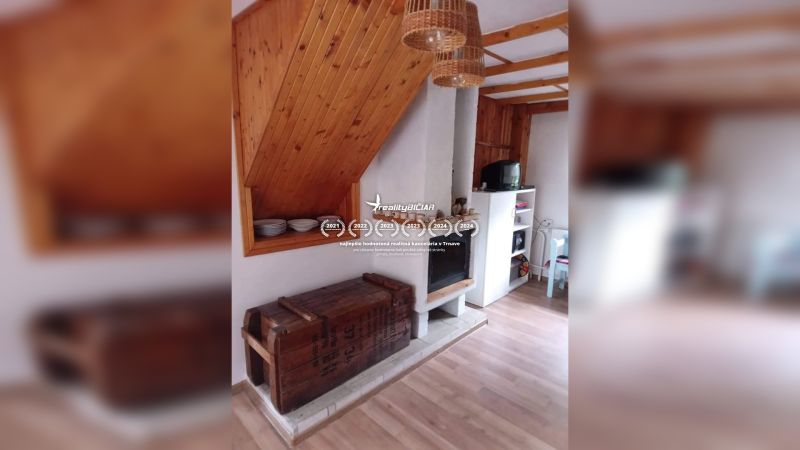 Exkluzívne na predaj, čarovný rodinný dom / chalupa v lone prírody - Interiér rodinného domu s krbom, podlahou s dreveným dekorom a úložným priestorom.