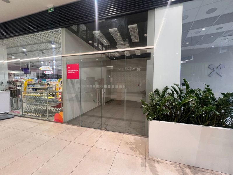 Na prenájom obchodný priestor 16,35m2 - Banská Bystrica/centrum NO099Z - Sklenená fasáda obchodného priestoru v nákupnom centre s oznamom o prerábke.