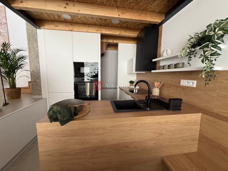 Na predaj: Nadštandardný 3-izbový rod. dom v Piešťanoch- Orviský kút - Moderná kuchyňa v rodinnom dome s dekorom dreva a čiernym drezom.