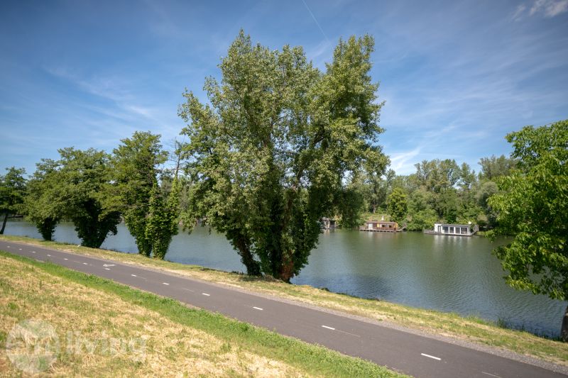 TOP LOKALITA - 3i 67m2 + loggia - Švermova Trenčín - Cesta popri rieke s loďami obklopená zeleňou na Švermovej ulici v Trenčíne.