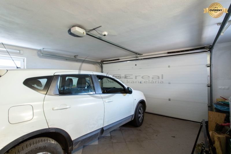NA PREDAJ priestranný 7-izbový rodinný dom s dvojgarážou v Marianke - Auto zaparkované v garáži rodinného domu s bielymi stenami a podlahou dlaždicami.