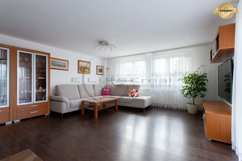 NA PREDAJ priestranný 7-izbový rodinný dom s dvojgarážou v Marianke - Obývacia izba v rodinnom dome s pohovkou, televízorom a podlahou s dreveným dekorom.