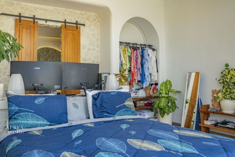 PREDAJ Unikátná 4KK Investičná zariadená vila s bazénom BALI-Jimbaran - Spálňa vo vile s posteľou, zelenými rastlinami a otvoreným šatníkom.